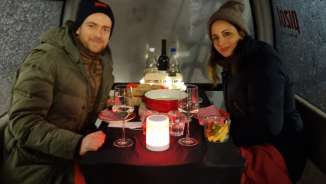 A couple enjoy a cheese fondue in a gondola and sit at a laid table