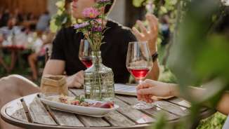 Wii-kend Maienfeld Couple sitting at a wooden table with summer decorations, snacks and a glass of wine