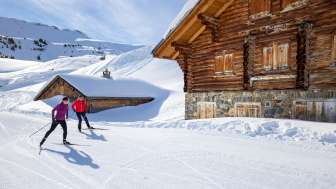 Two cross-country skiers on the Flumserberg in front of a hut Two cross-country skiers on the Flumserberg in front of a hut