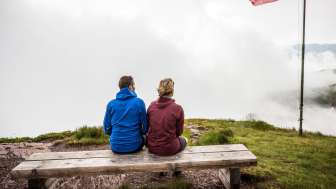 Hiking in any weather Couple sitting on a bench in the fog