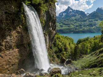 The thundering waterfall of the Rhinquelle with a view of Lake Walen and the striking Mürtschenstock