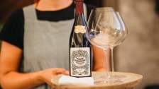 Woman serving a bottle of wine with glasses